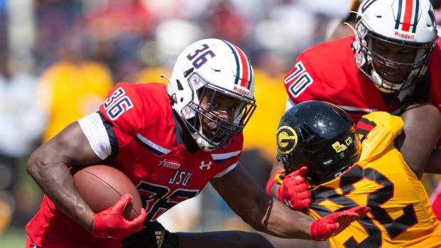 Jackson State running back Sy'veon Wilkerson (26) pushes forward as offensive lineman Kirk Ford (70) holds back Grambling defensive lineman Wesley Green (92) during an NCAA college football game in Jackson, Miss.